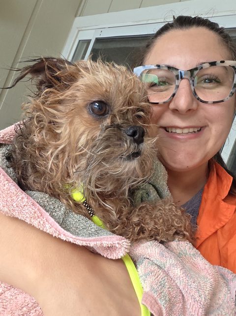 Alexis Moody smiling with a freshly bathed dog wrapped in a towel